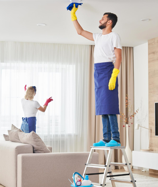 Cleaner Dallas team performing high-reach ceiling and window cleaning in a modern living room