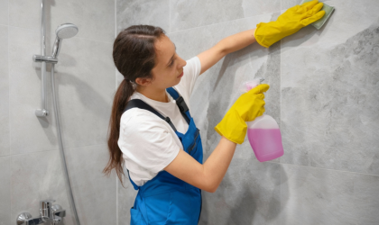 Cleaner Dallas professional cleaner scrubbing bathroom tiles with cleaning spray and sponge.