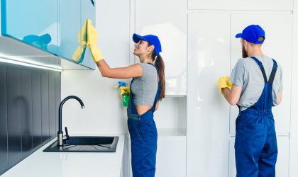 Cleaner Dallas team wiping kitchen cabinets and sanitizing surfaces in modern home.