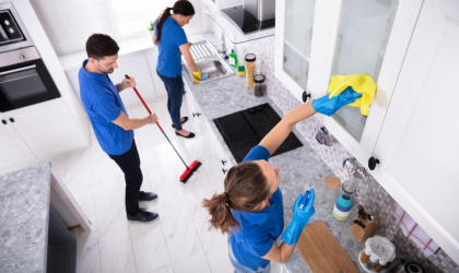 Cleaner Dallas team performing detailed kitchen cleaning including cabinet wiping, sweeping, and sink sanitizing.
