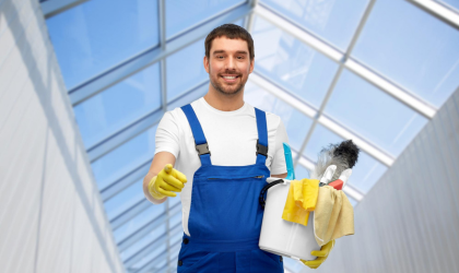 Cleaner Dallas professional holding cleaning supplies inside a bright commercial building
