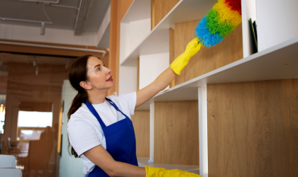 Dallas house cleaner dusting shelves during professional home cleaning service.