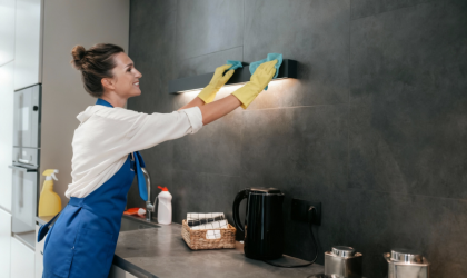 Professional kitchen cleaning service in Dallas wiping stove hood and wall surface