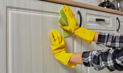 Professional kitchen cabinet cleaning in Dallas wiping grease from cabinet doors.