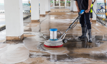 Worker using a floor scrubber machine to clean and polish concrete surfaces after construction